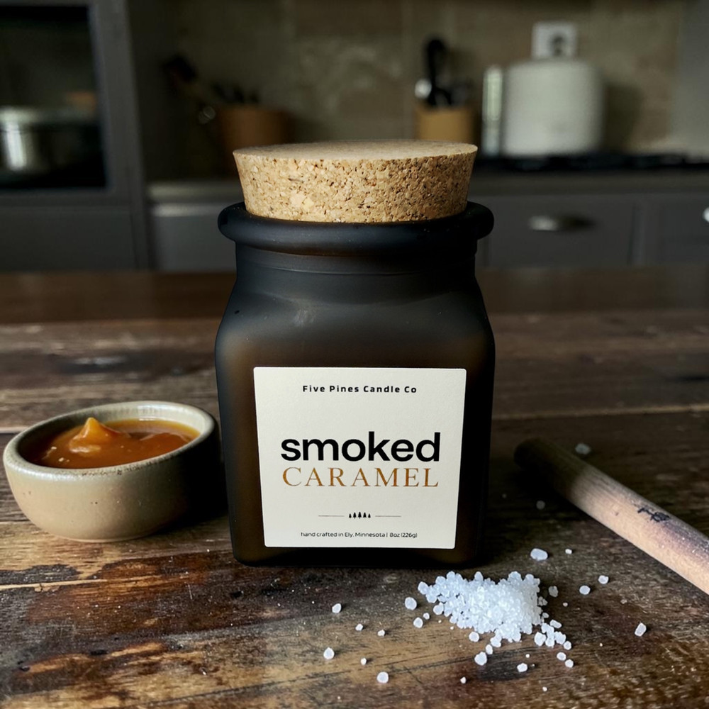 Smoked Caramel candle in dark amber glass beside caramel and sea salt